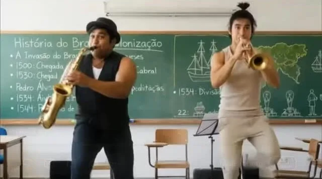 Dois músicos tocando sax e trompete numa sala de aula